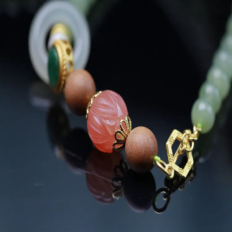 Hetian jade necklace with lotus beads, zodiac charm, and matching bracelet on white background