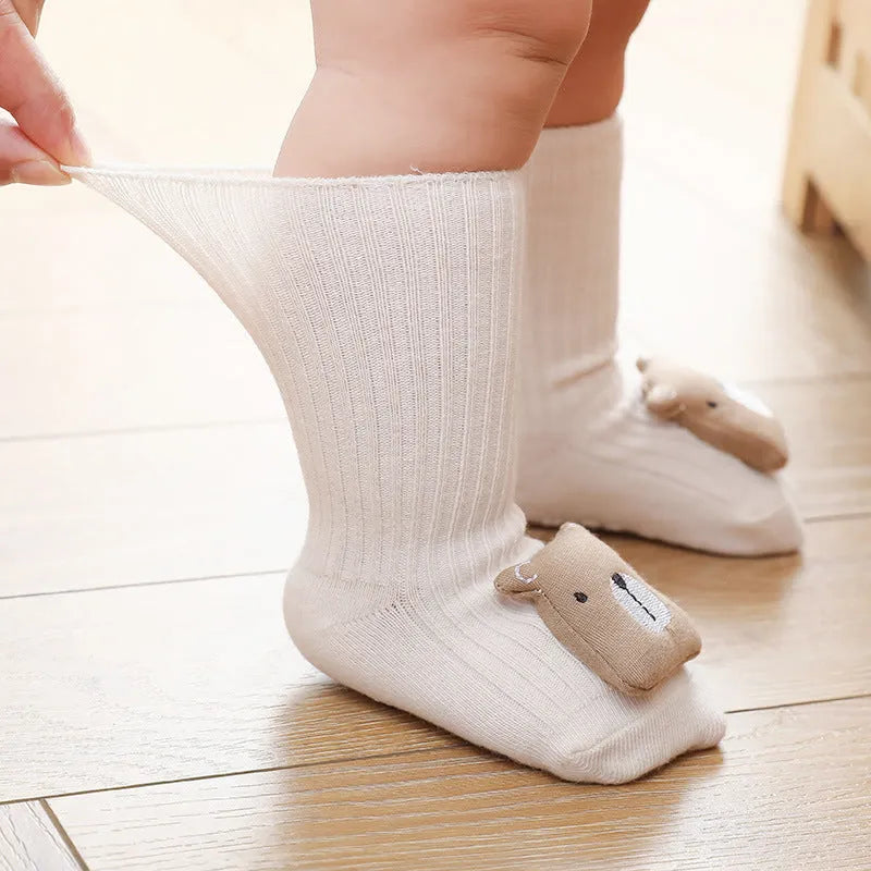 Baby socks with non-slip rubber grip soles on the feet, shown in a light grey colour.