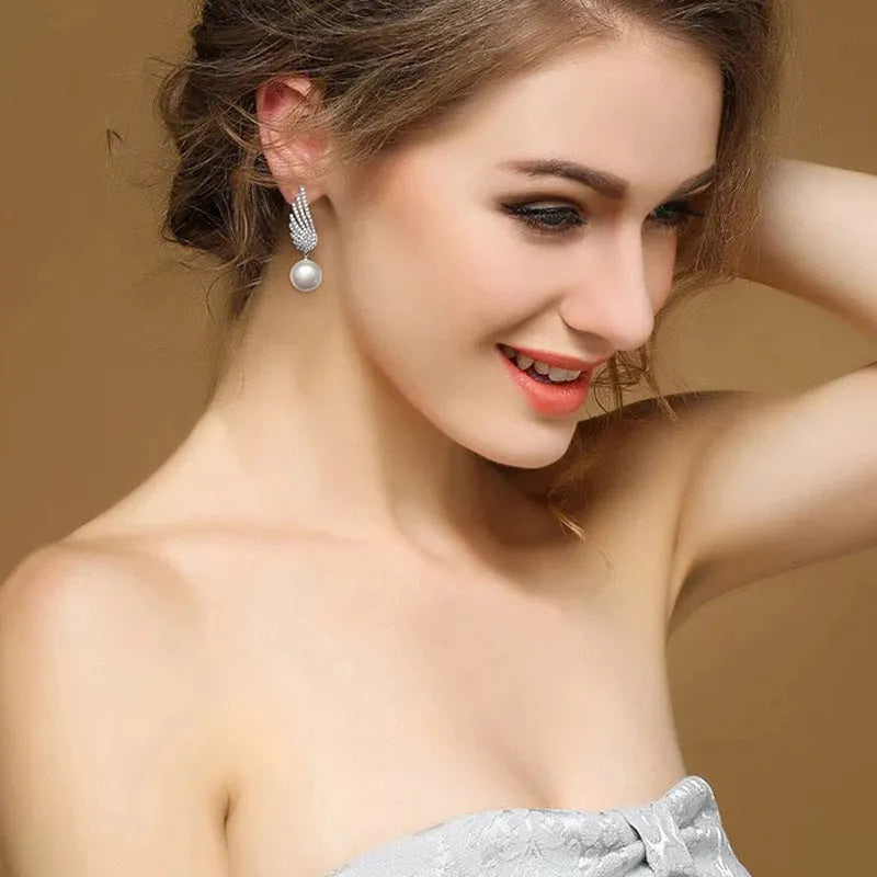 A pair of sterling silver angel wing earrings with diamond cut details and gold-plated gemstone inlay.