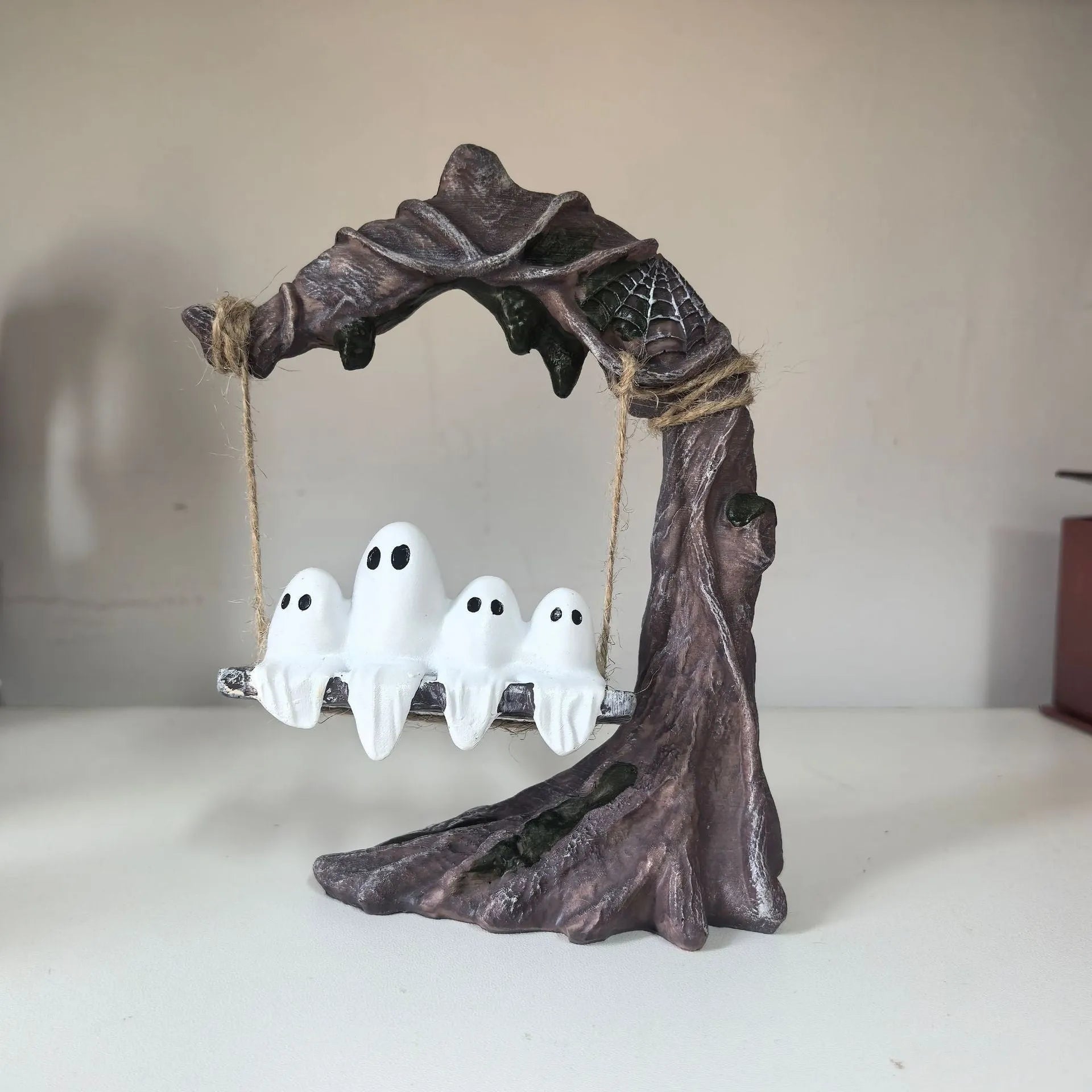 Modern Halloween decoration featuring a stylised white resin ghost on a black swing frame, with two design options shown.