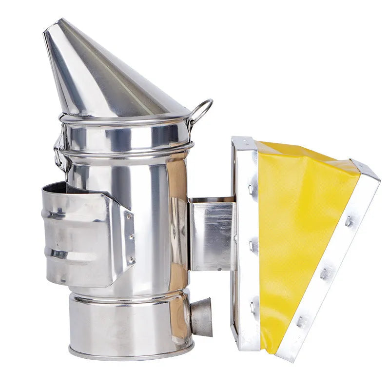 Stainless steel bee smoker with leather bellow on a wooden table against a blurred outdoor background