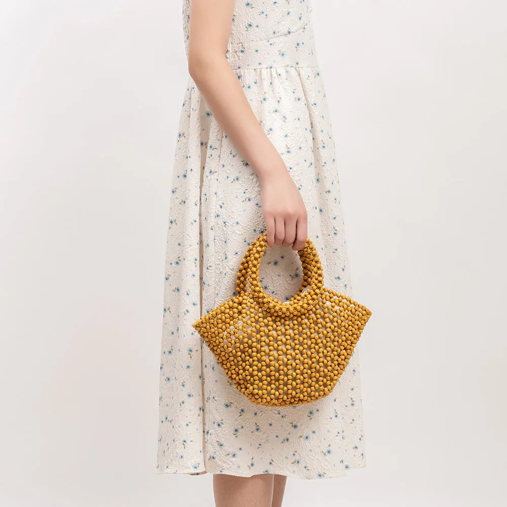 Hand-woven dumpling-shaped handbag with wooden beads in milky white colour