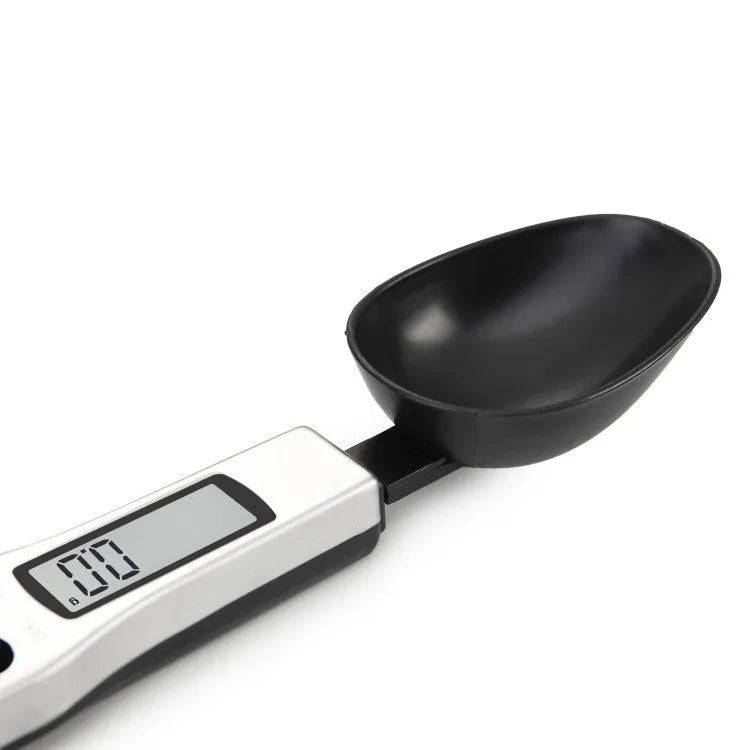 Black digital measuring spoon with LCD display showing weight measurement for kitchen use