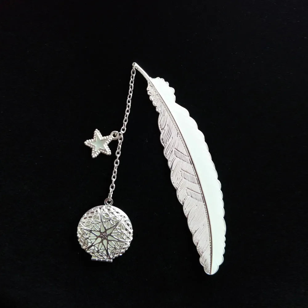 Silver pure copper feather bookmark with glowing luminous butterfly charm on a book.