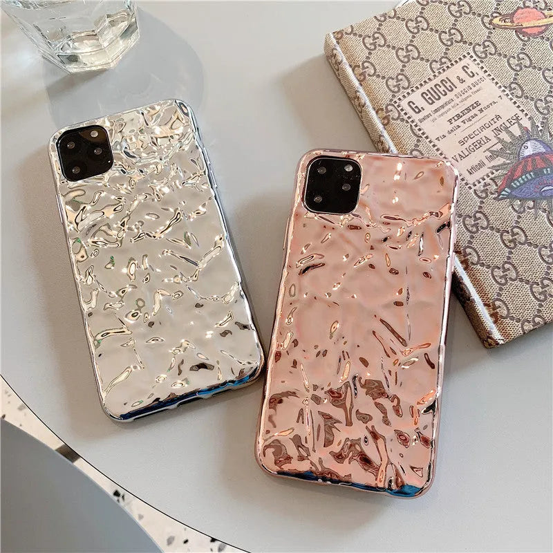 Rose gold and silver folded TPU back cover cases for various iPhone models on a plain surface.