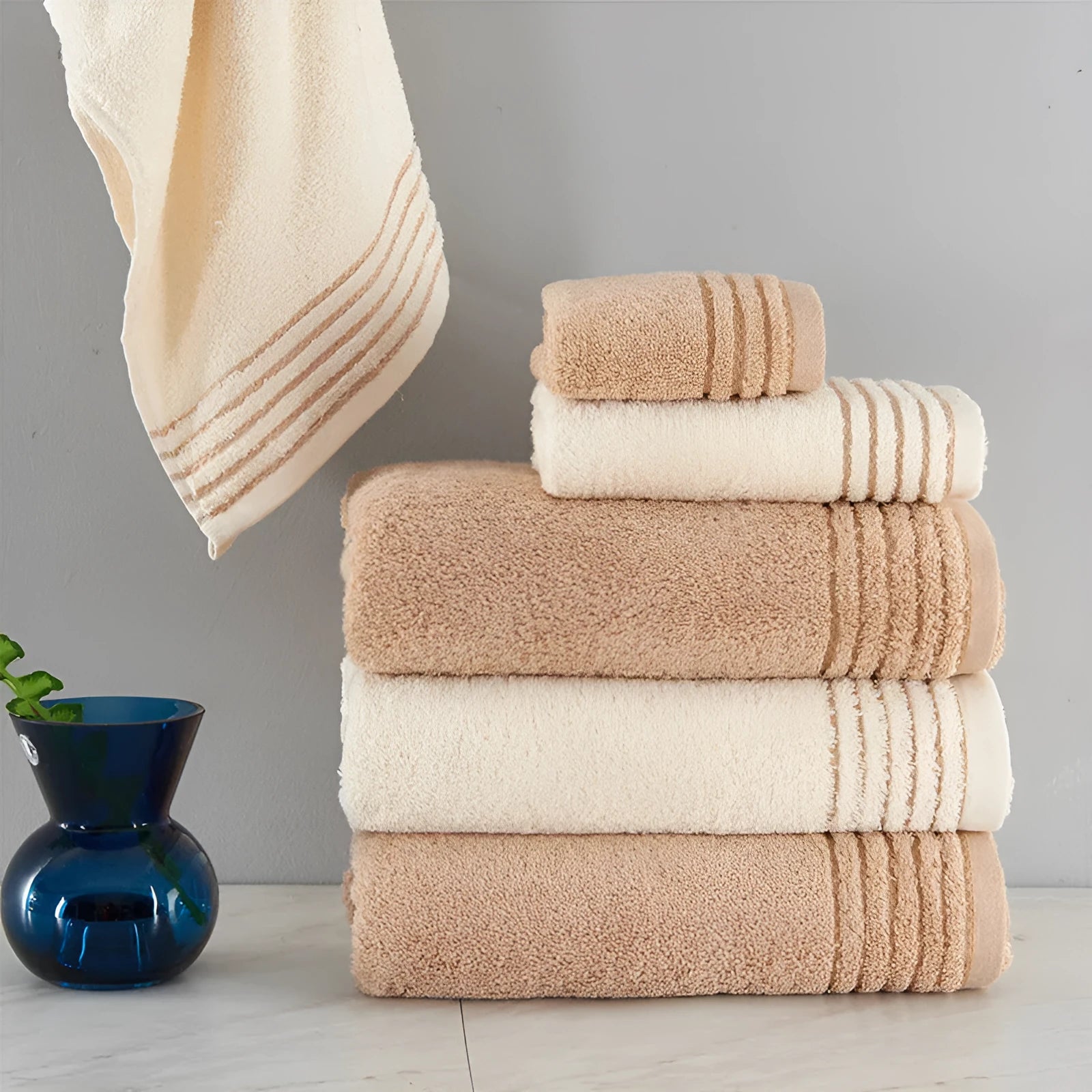 Set of three cotton towels in beige and brown colours, showing small, medium, and large sizes.