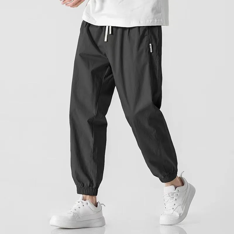Men's loose cuffed cargo pants in black polyester fabric with cuffed hem and relaxed fit