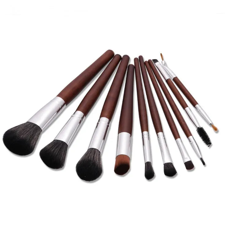 10 brown makeup brushes with wooden handles and nylon bristles laid out on a flat surface