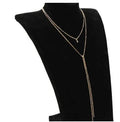 Multilayer lariat necklace in gold with three alloy chains on a plain background