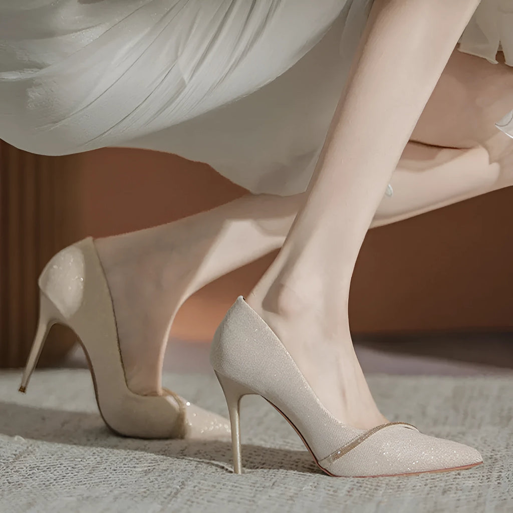 Gold women's pointed toe stiletto high heels with a low cut design on a plain background.