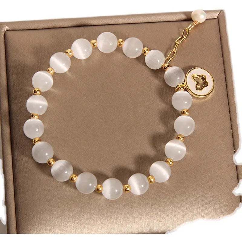 White Cat's Eye crystal bracelet with geometric links on a wrist.