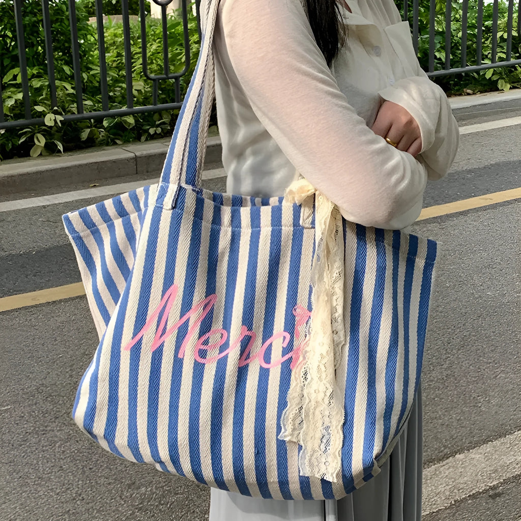 Blue, pink, and white striped canvas bag with printed letters on the front.
