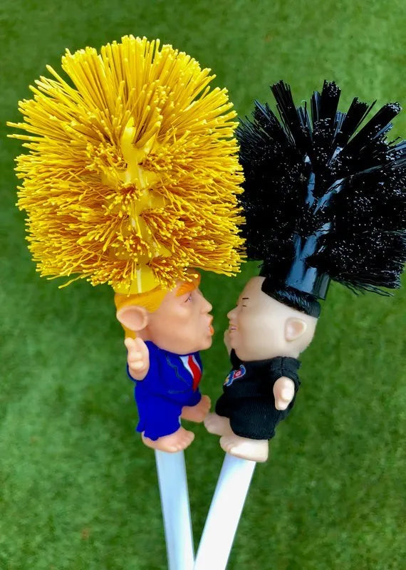 Yellow plastic Donald Trump toilet brush with hanging slot on handle.