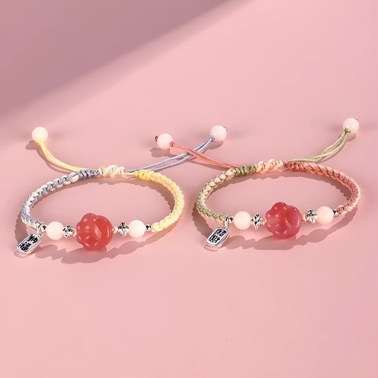 Red cat's paw glass bead on a handmade pink woven bracelet for couples.