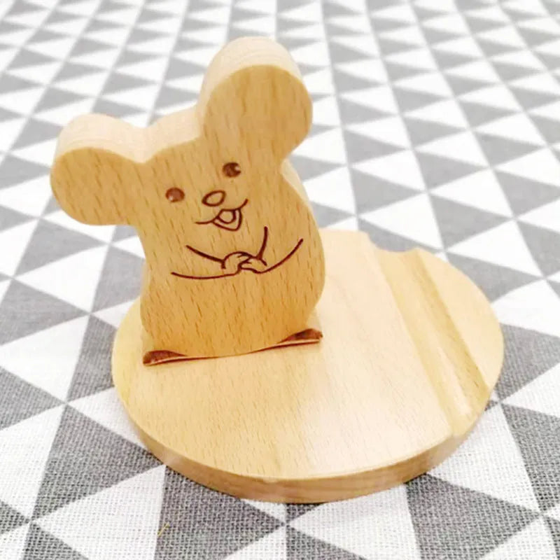 Beech wood and resin lazy bracket mobile phone holder in an animal design style on a desk.