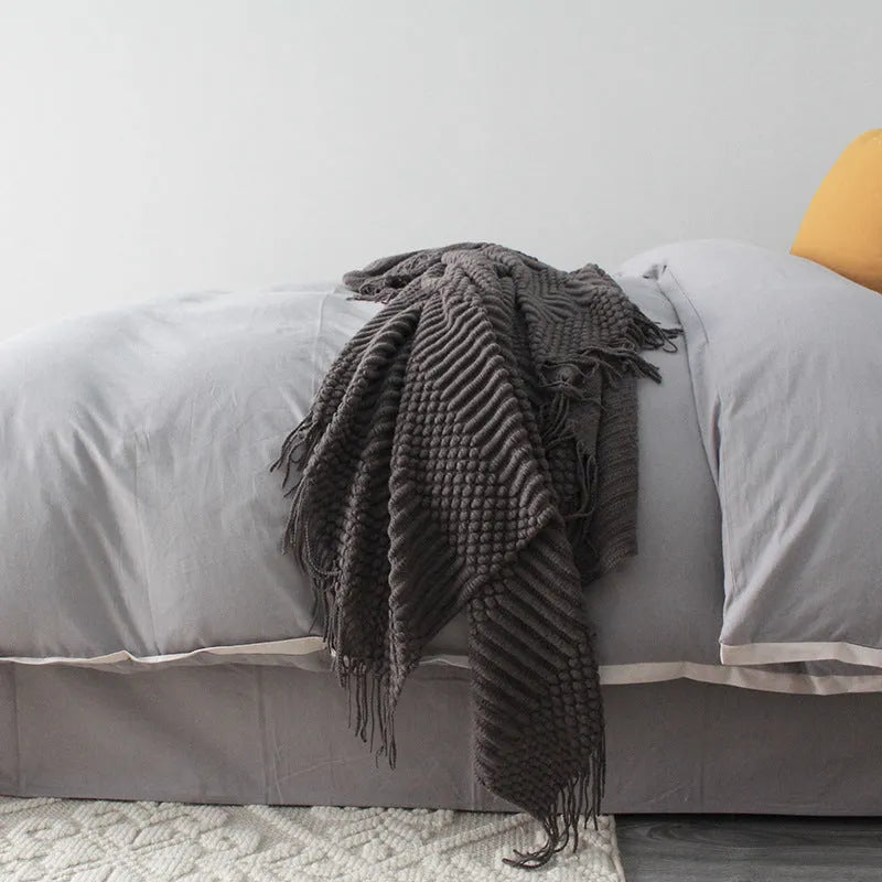 Small rectangular nap blanket in a neutral colour, showing its compact size relative to a hand.