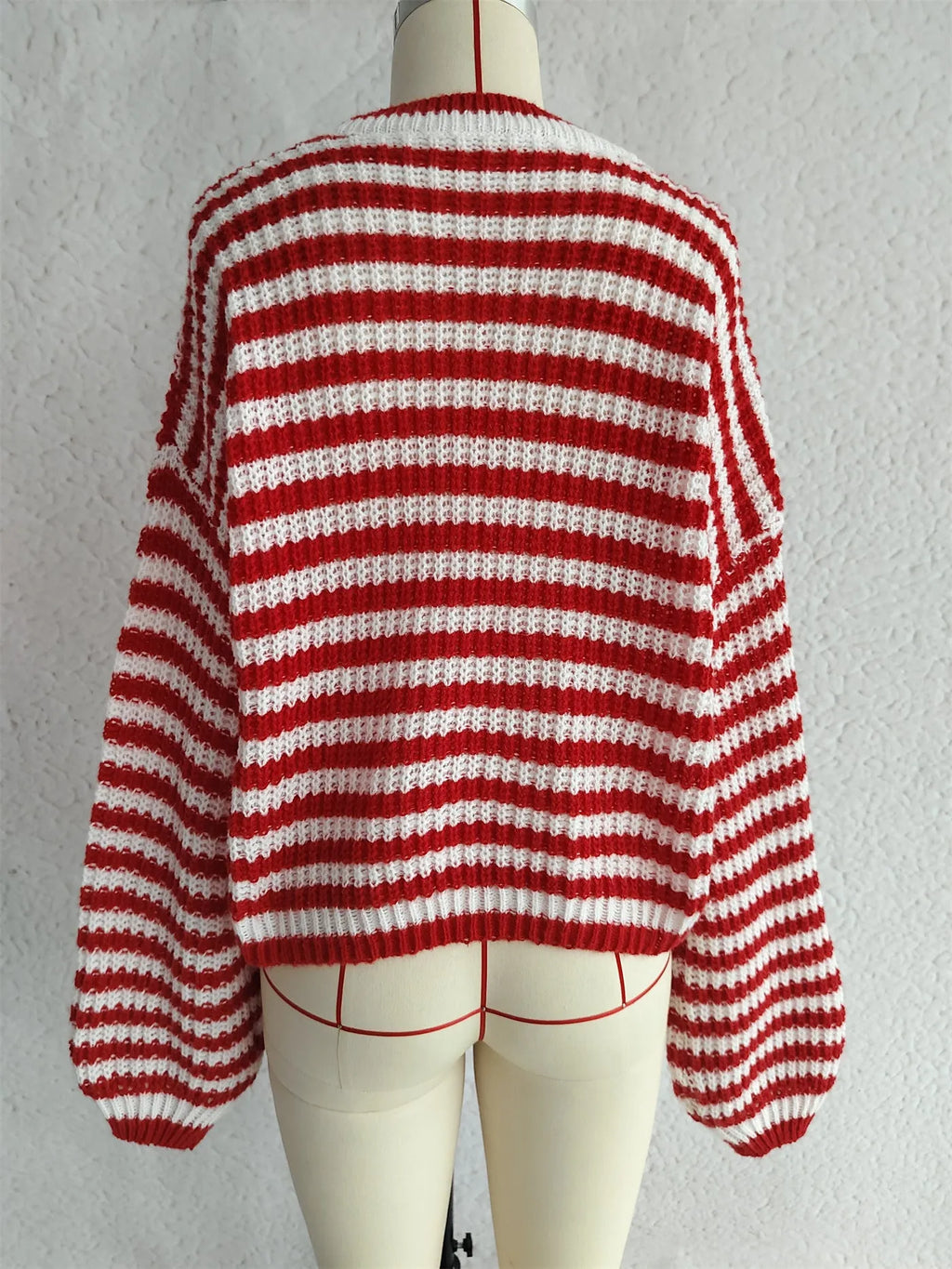Woman wearing a loose black and white stripe pullover sweater with a round neck and long sleeves.