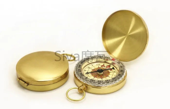 Gold metal flip compass with open lid showing compass face, pocket watch style