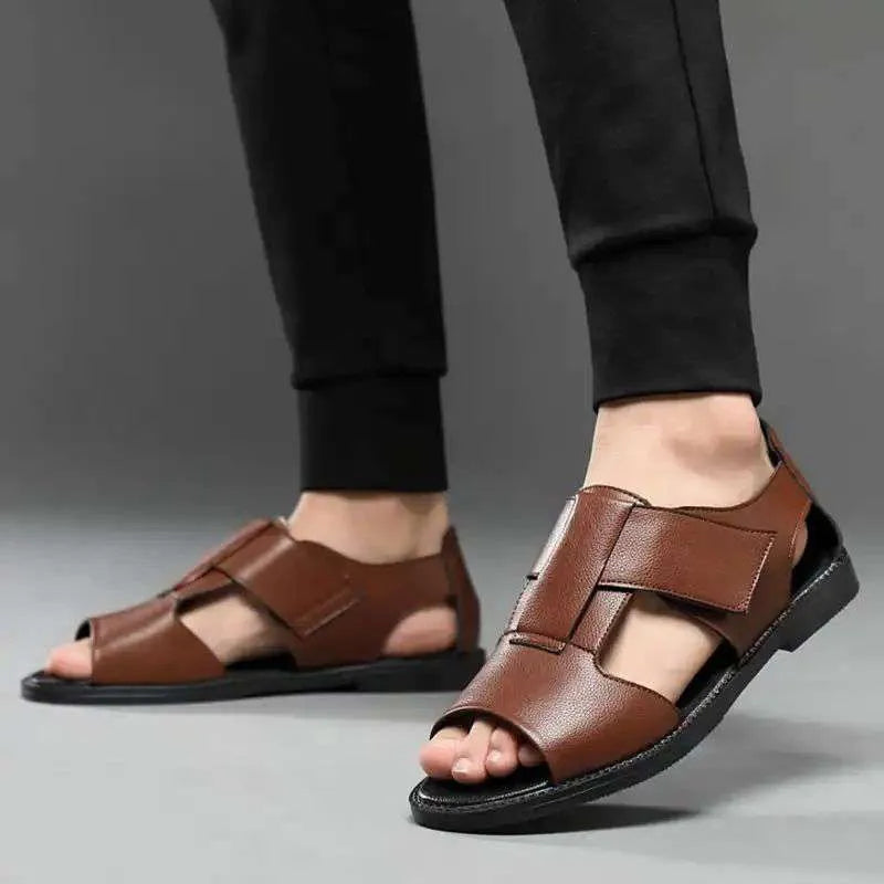 Men's black and brown leather open-toe Roman sandals with a rubber sole on a plain background.