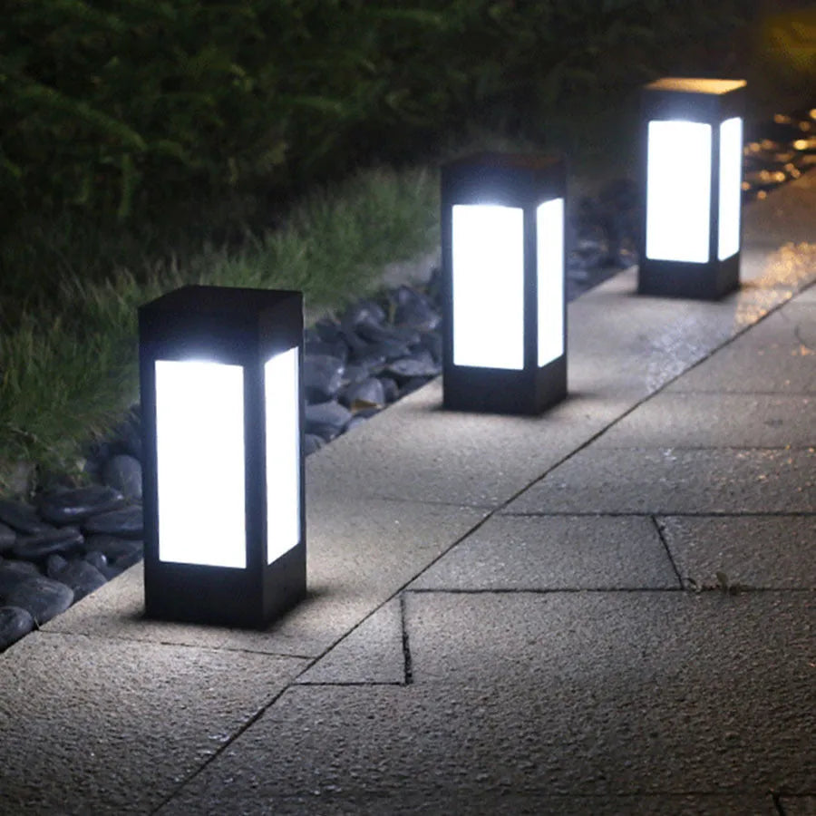 A set of waterproof solar-powered garden lights installed along a lawn edge and wall.