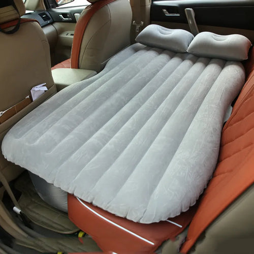 Inflatable car bed with flocked surface folded beside two pillows in storage bag for vehicle sleeping