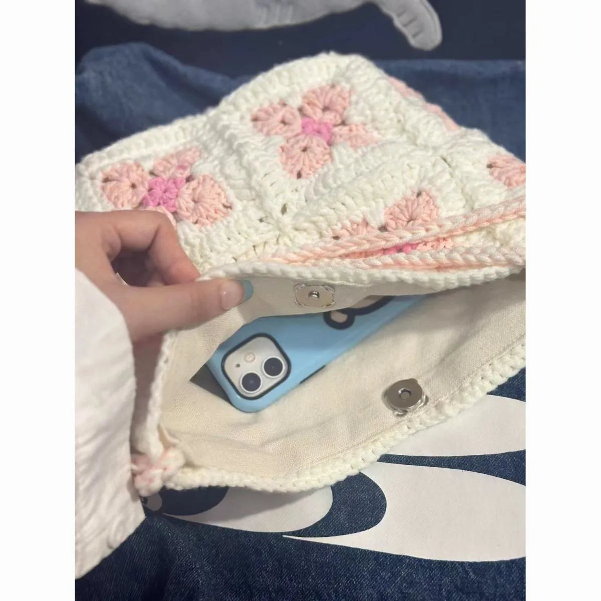 Handmade pink crochet handbag with cherry blossom design and magnetic buckle.