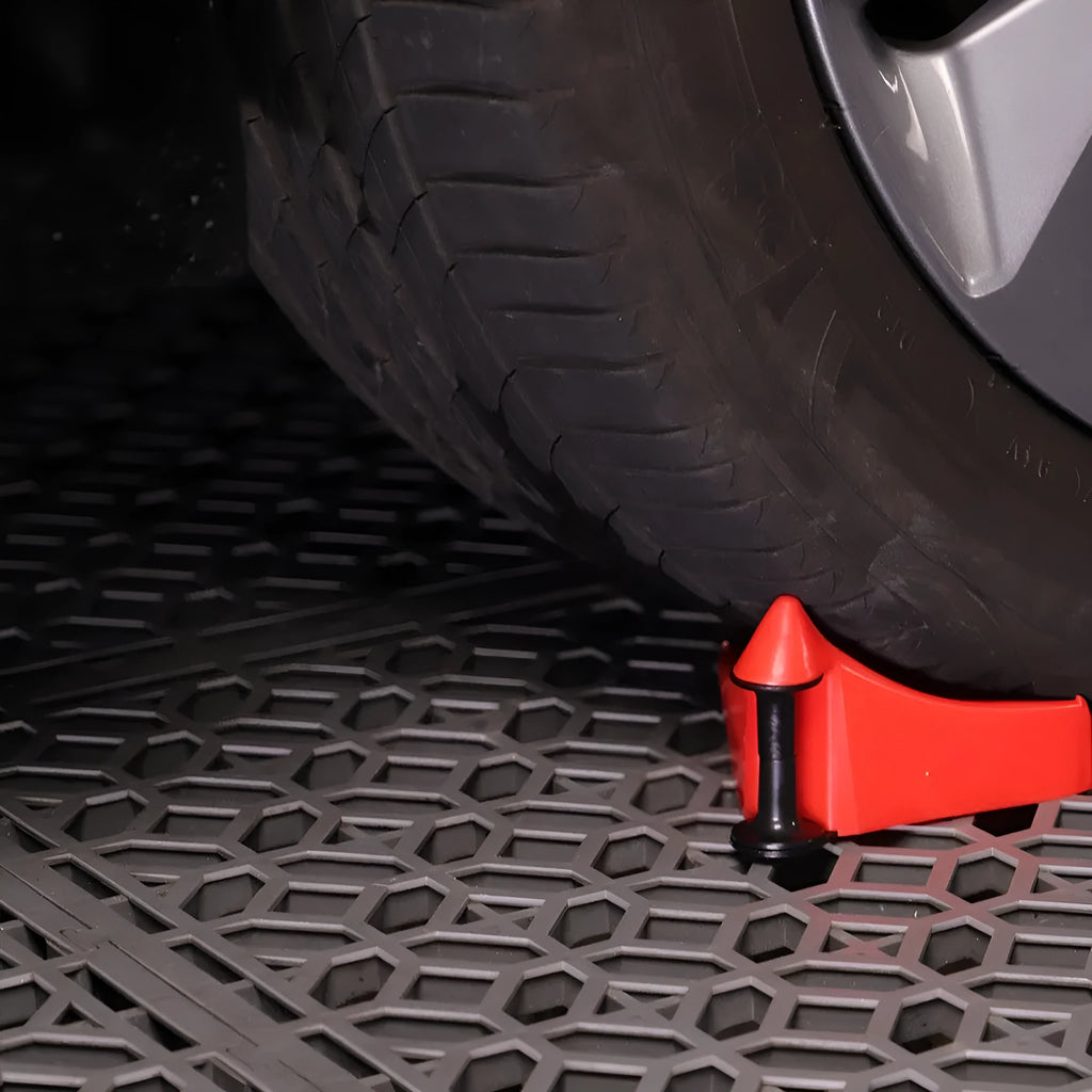 Set of four bright red triangular plastic parking wheel chocks on a grey background