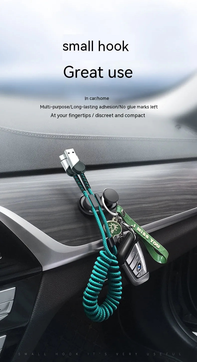 Dark green ABS silicone car cable hook with adhesive backing for organising data cables on a dashboard.