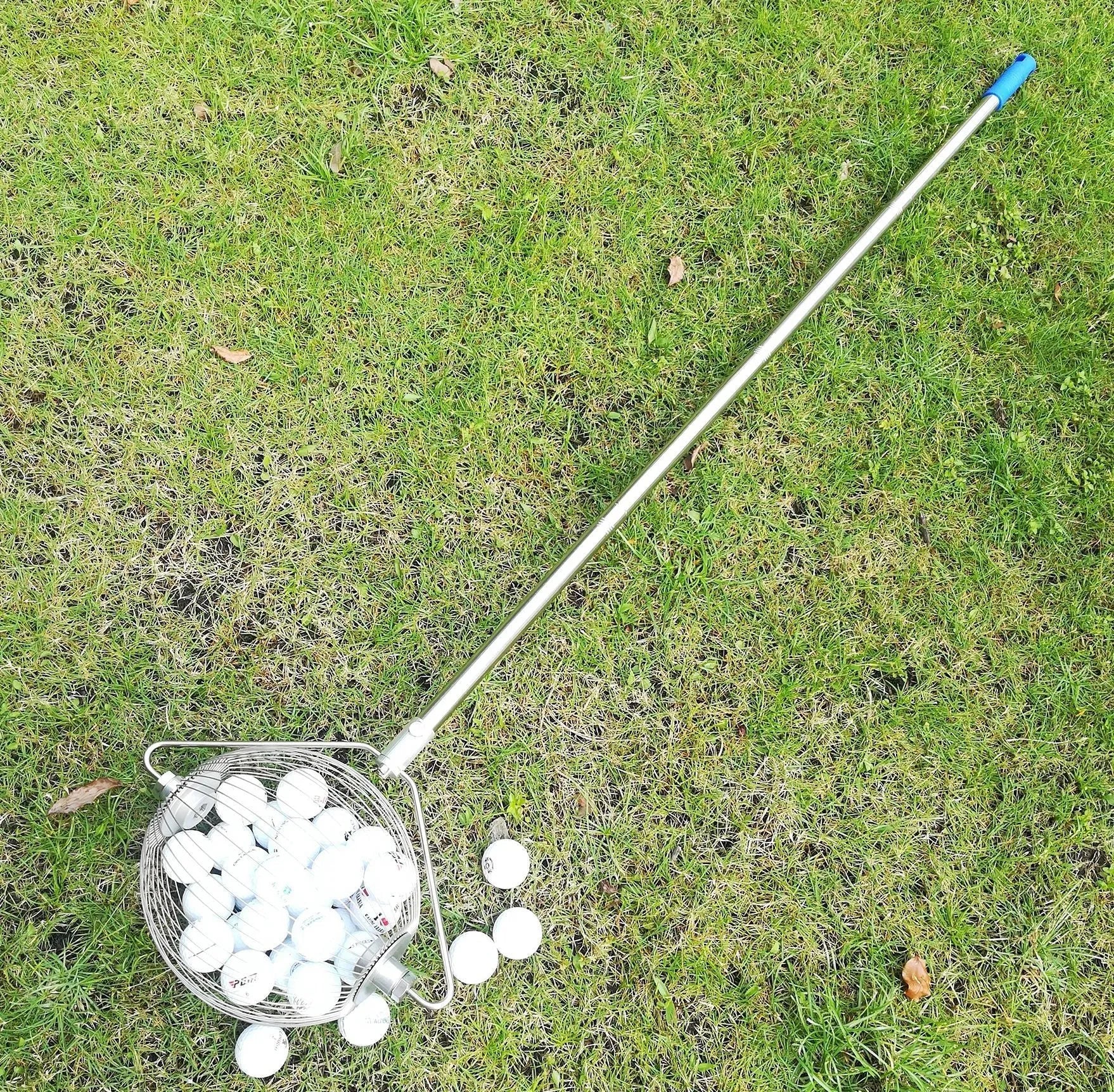 Metallic stainless steel golf ball picker on green grass