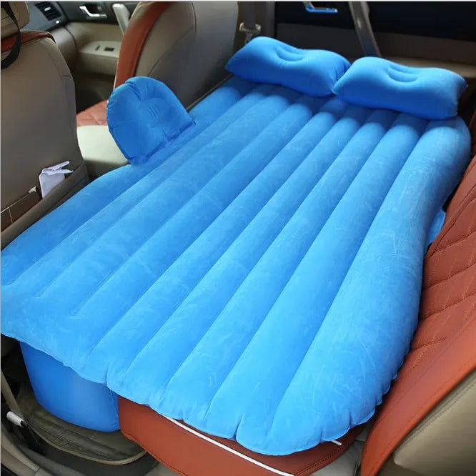 Black inflatable car bed with flocked surface, shown with storage bag and pillows, ready for use in a vehicle.