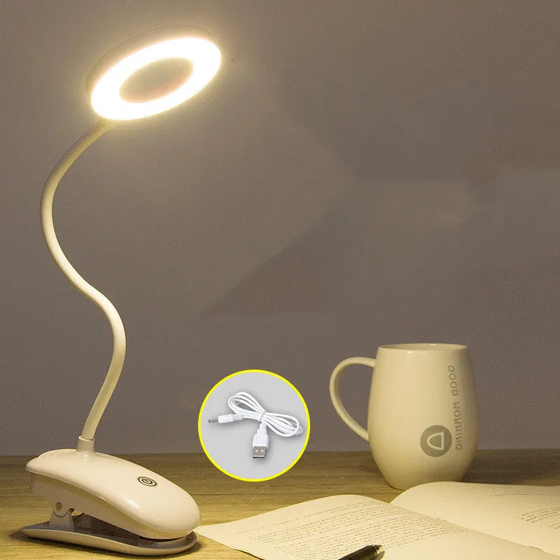 Modern clip-on rechargeable desk lamp with a white plastic shade and touch controls on its base.