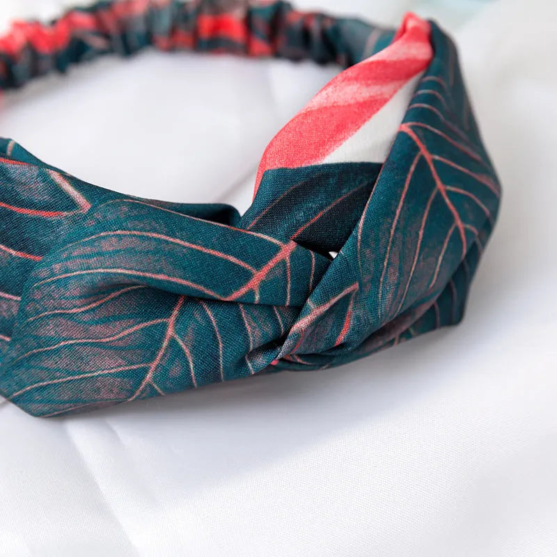 Red cloth women's headband with a banana leaf cross shaped hair decoration.
