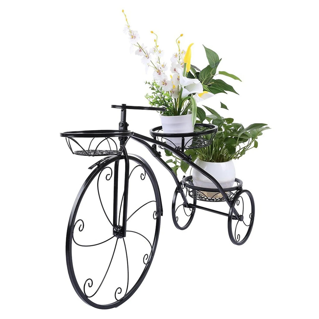 Black wrought iron tricycle plant stand with three round baskets holding small potted plants on a patio