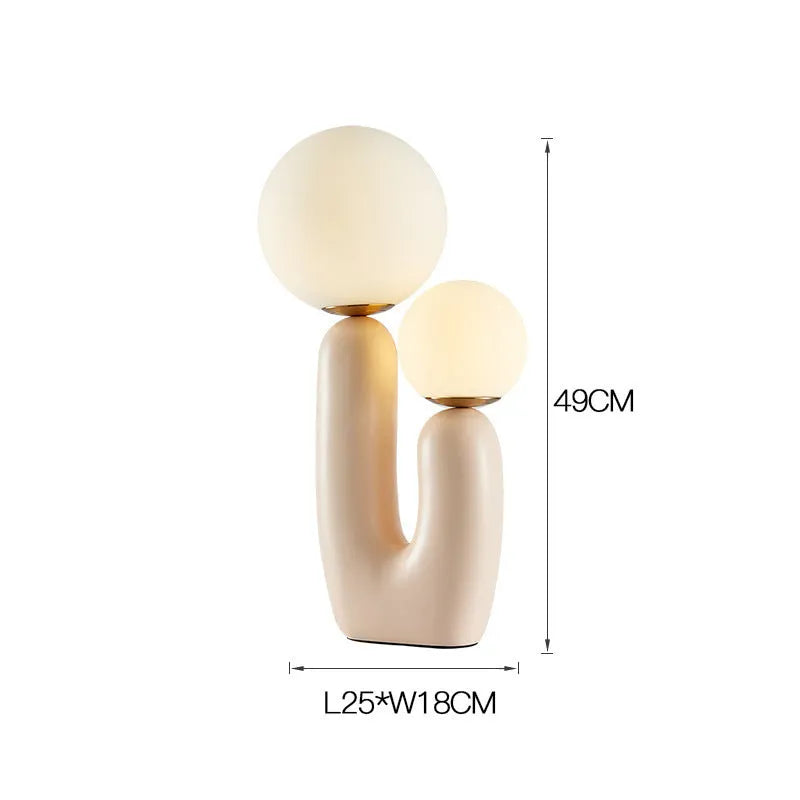 Pink double-head resin table lamp with glass shade on a bedside table, 49cm tall