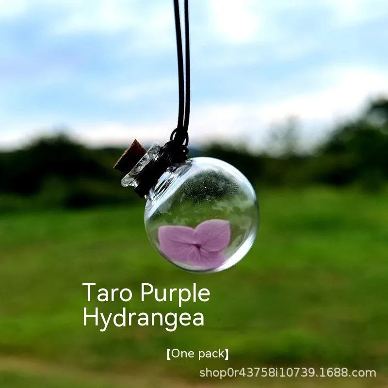 Glass car perfume pendant with preserved flower decoration hanging in car interior
