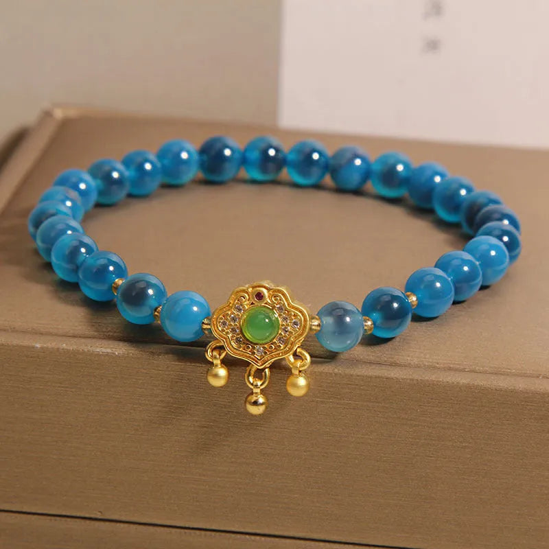 Blue sugar heart agate safety lock pendant on a women's crystal bracelet with rhinestone details.