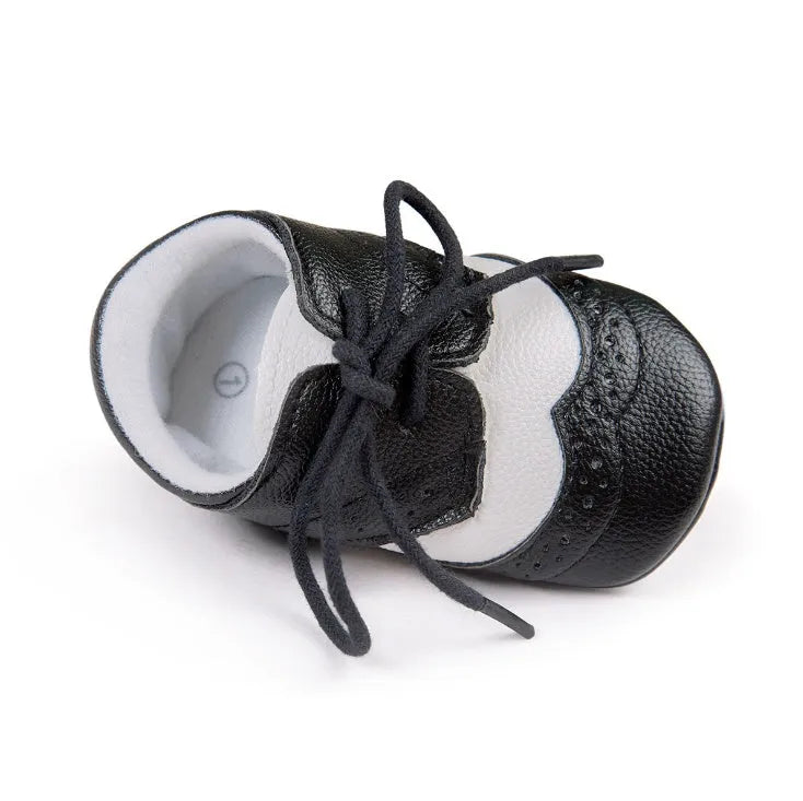 Vintage-style soft-soled baby shoes in black, grey, light brown, and white for infants 0-12 months.