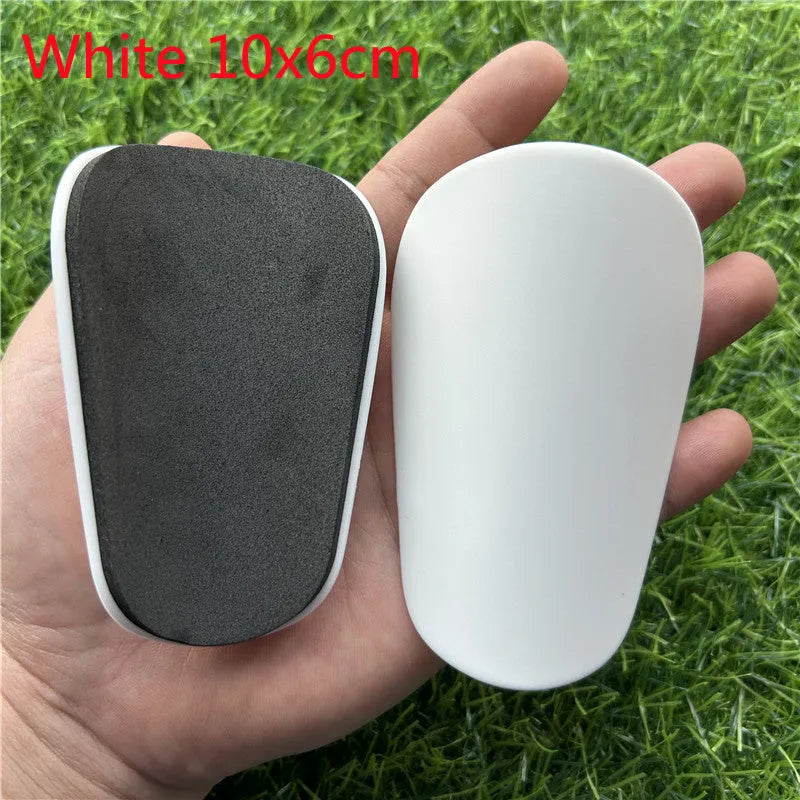 Pair of extra small black and white plastic football shin guards, measuring 8cm by 5cm.