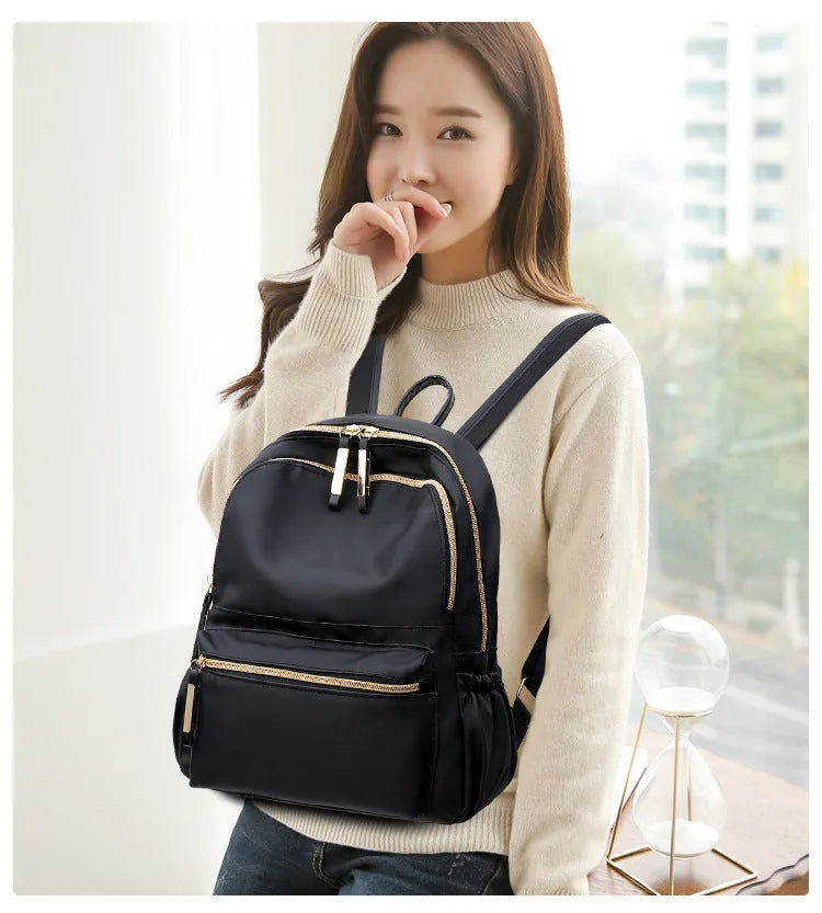 Black waterproof Oxford cloth backpack for women, 34x26x13cm, with two straps and front pocket on plain background