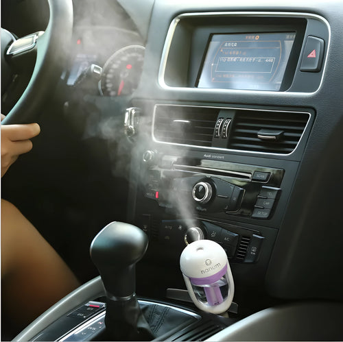 Compact blue portable car humidifier and essential oil diffuser with rotating nozzle on a car dashboard.