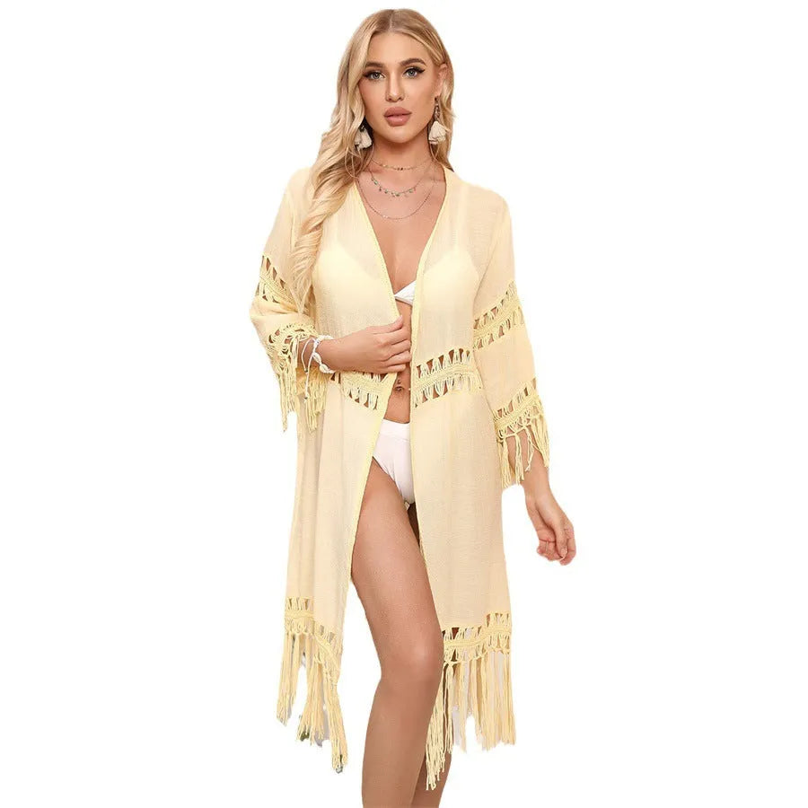 Yellow hand-crocheted women's beach cardigan with tassel trim on a hanger.