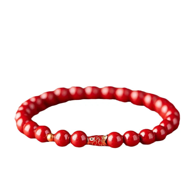 Natural cinnabar koi bracelet with golden ball in national style on a wrist.