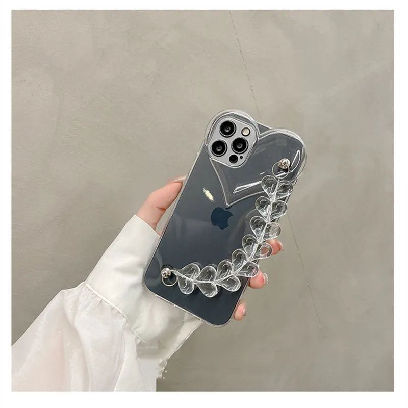 Clear iPhone case with transparent love heart bracelet charm attached, showing soft TPU material.