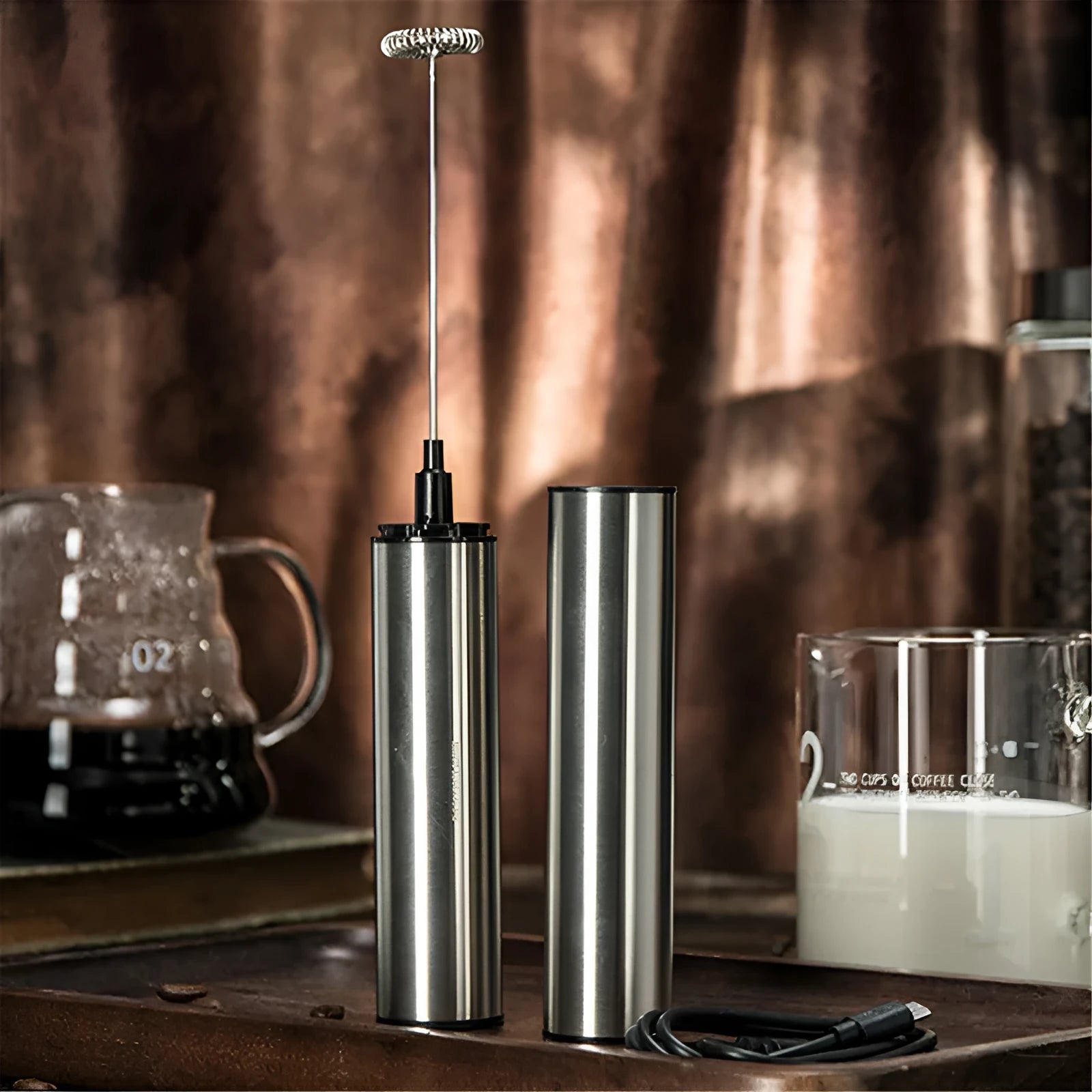 Silver handheld electric milk frother with double teat stainless steel whisk head on white background