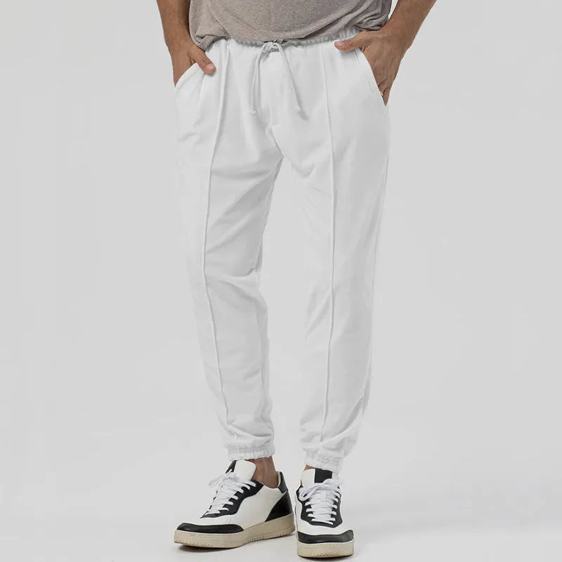 Man wearing grey loose tapered cotton blend track sweatpants with a straight leg.