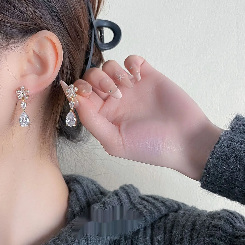 Gold flower tassel stud earrings with copper electroplated finish on light background