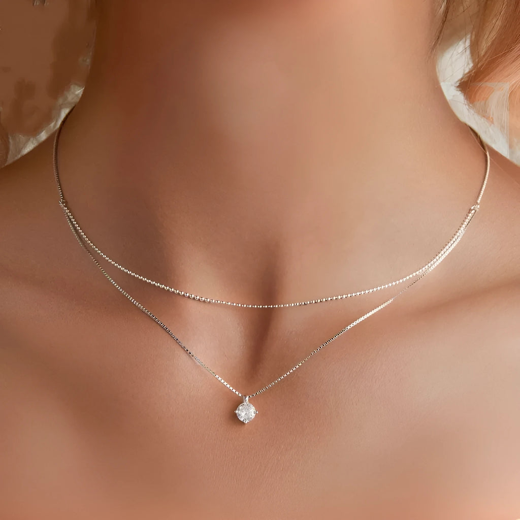 Close-up of a double-layer sterling silver necklace with a pearl-style chain, showing its layered design and silver finish.