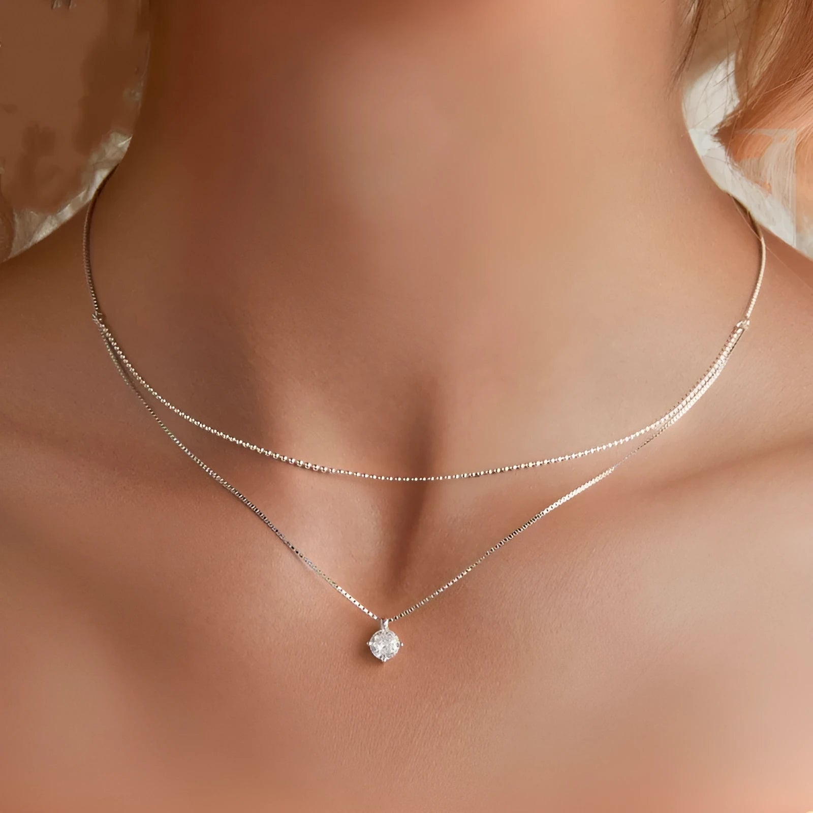 Close-up of a double-layer sterling silver necklace with a pearl-style chain, showing its layered design and silver finish.