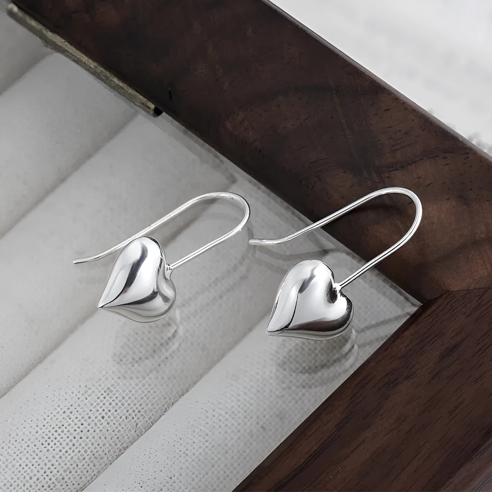 Silver heart-shaped women's earrings with glossy finish and three-dimensional design