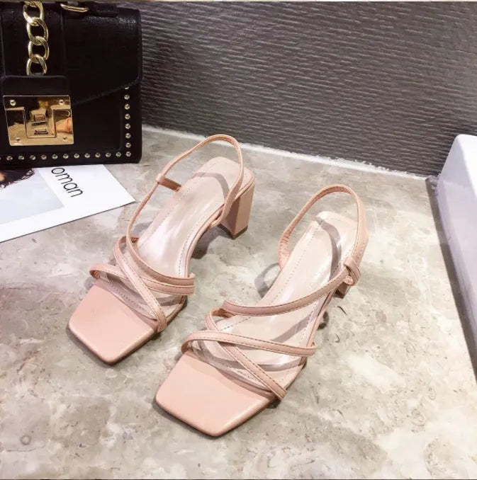 Women's white thick high heel slip-on sandals with a backless design on a plain background.